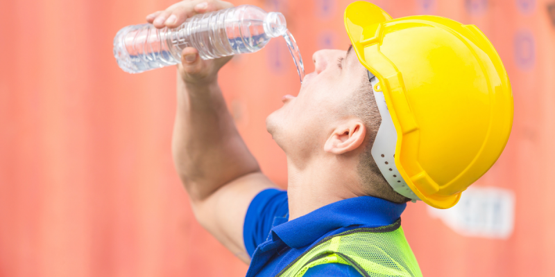 Worker in a hard hat drinking water